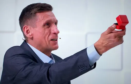 Юрий встал на колено и протянул девушке кольцо в красной коробочке Юрий встал на колено и протянул девушке кольцо в красной коробочке